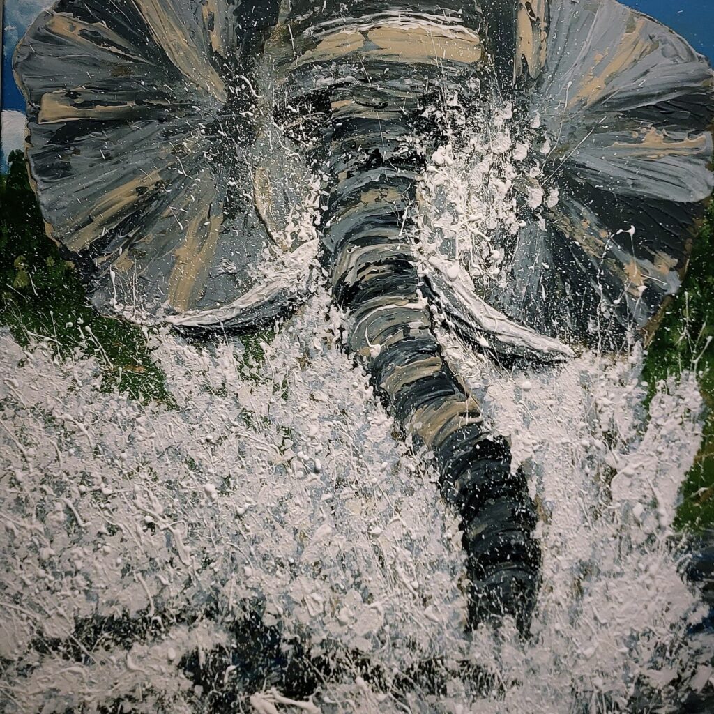 Ein Elefant der anscheinend gerade viel Spaß im Bad hat, er verschwindet halb unter den Wassertropfen