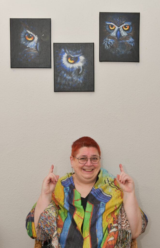 ich vor einer Wand mit drei Eulenbildern von mir