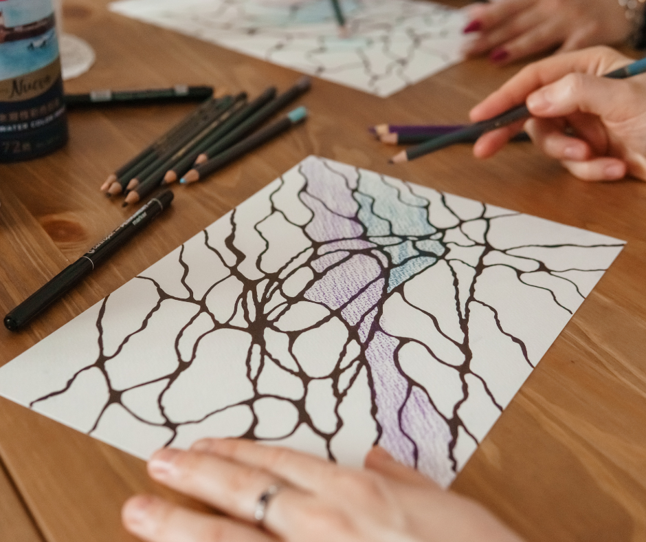 auf dem Tisch liegt ein Blatt papier mit einer begonnenen Neurographischen Zeichnung und ein paar Stifte, freies Neurozeichnen