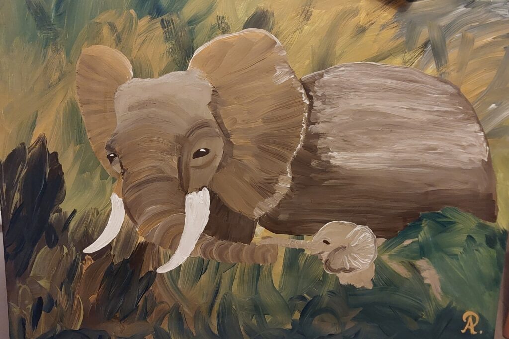 Ein großer Elefant der durch hohes Gras geht, den Babyelefanten sieht man nur teilweise, das Gras ist zu hoch