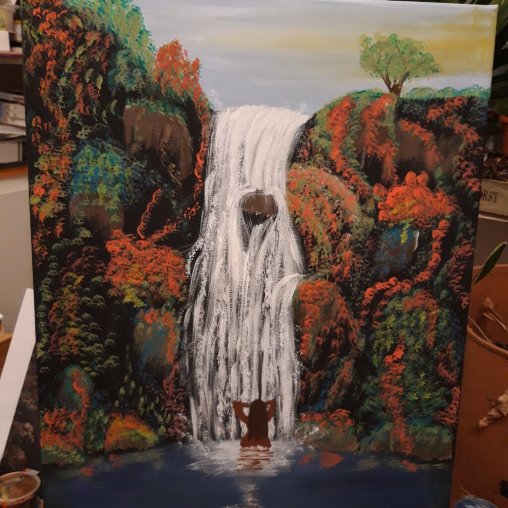 Ein Wasserfall, unten ein see in dem eine Frau steht und sich im Wasserfall duscht