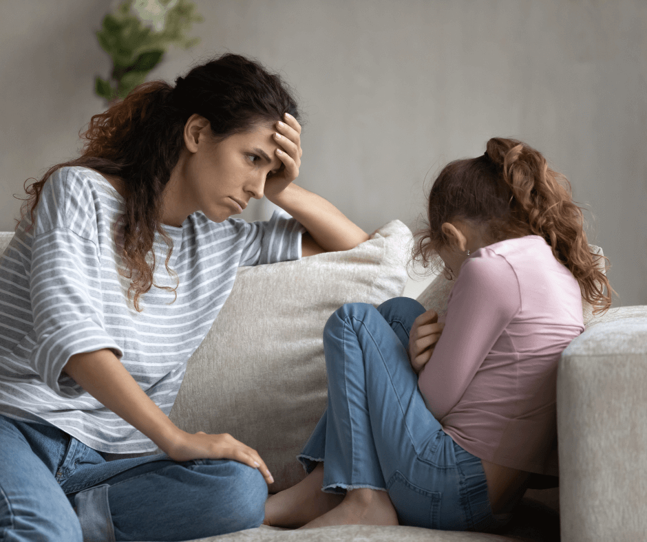 eine Junge Frau sitzt einem Mädchen gegenüber, beide scheinen Schuldgefühle zu haben nach einem Streit