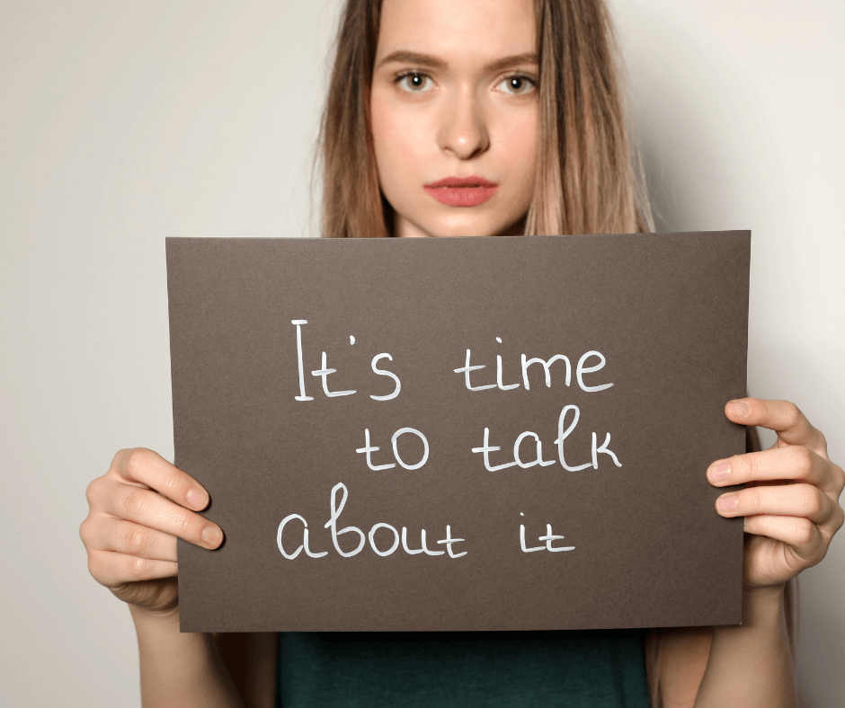eine junge Frau hält ein Schild vor sich, darauf steht "its time to talk about it"