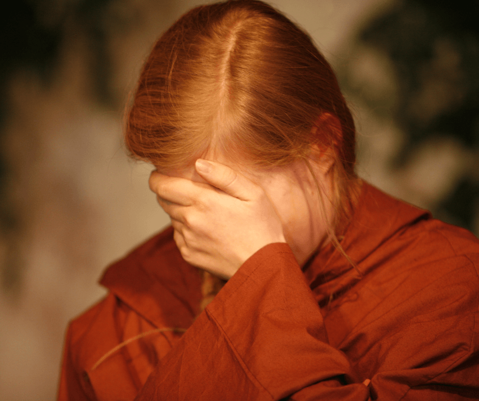 Eine Frau hält das Gesicht mit der Hand bedeckt
