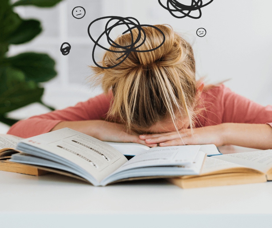 Eine Frau legt ihren Kopf erschöpft auf den Tisch, über ihrem Kopf sind schwarze Gedankenkringel